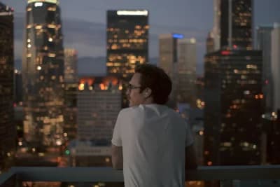 Her filmi Joaquin Phoenix Theodore karakteri balkonda Los Angeles gece manzarasına bakıyor, kulağında kulaklık var